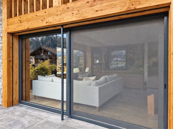 Grande moustiquaire coulissante devant une baie de chalet