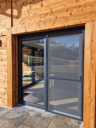 Moustiquaire battante devant une porte-fenêtre de chalet